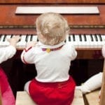 Three little baby girls playing a piano